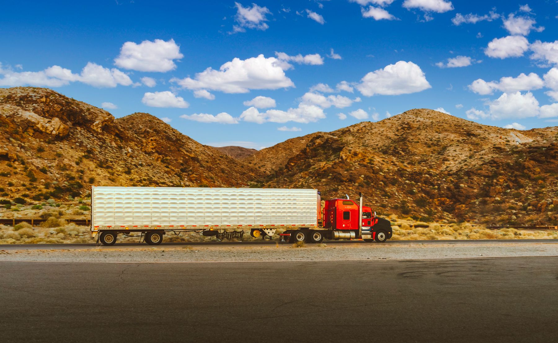 A Happy Transport tractor-trailer hauling across a sunlit mountain highway